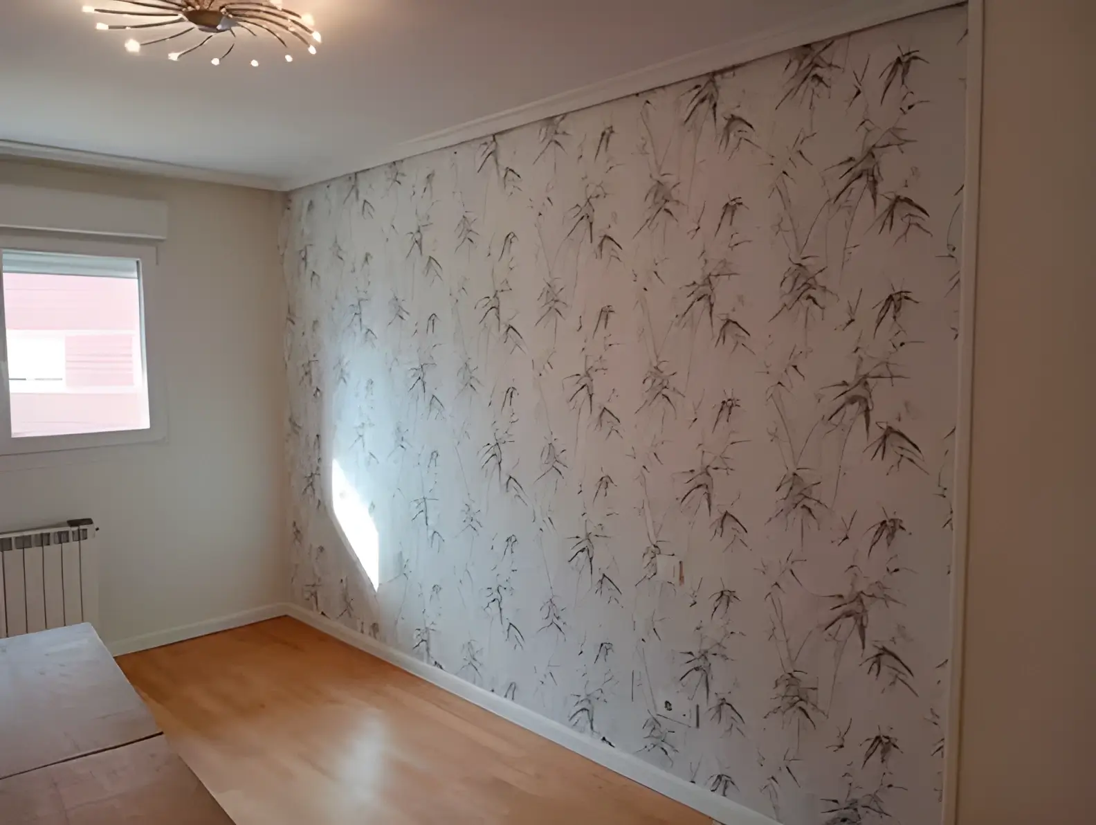 Pintores en Badajoz colocando papel pintado en pared de acento de habitación luminosa