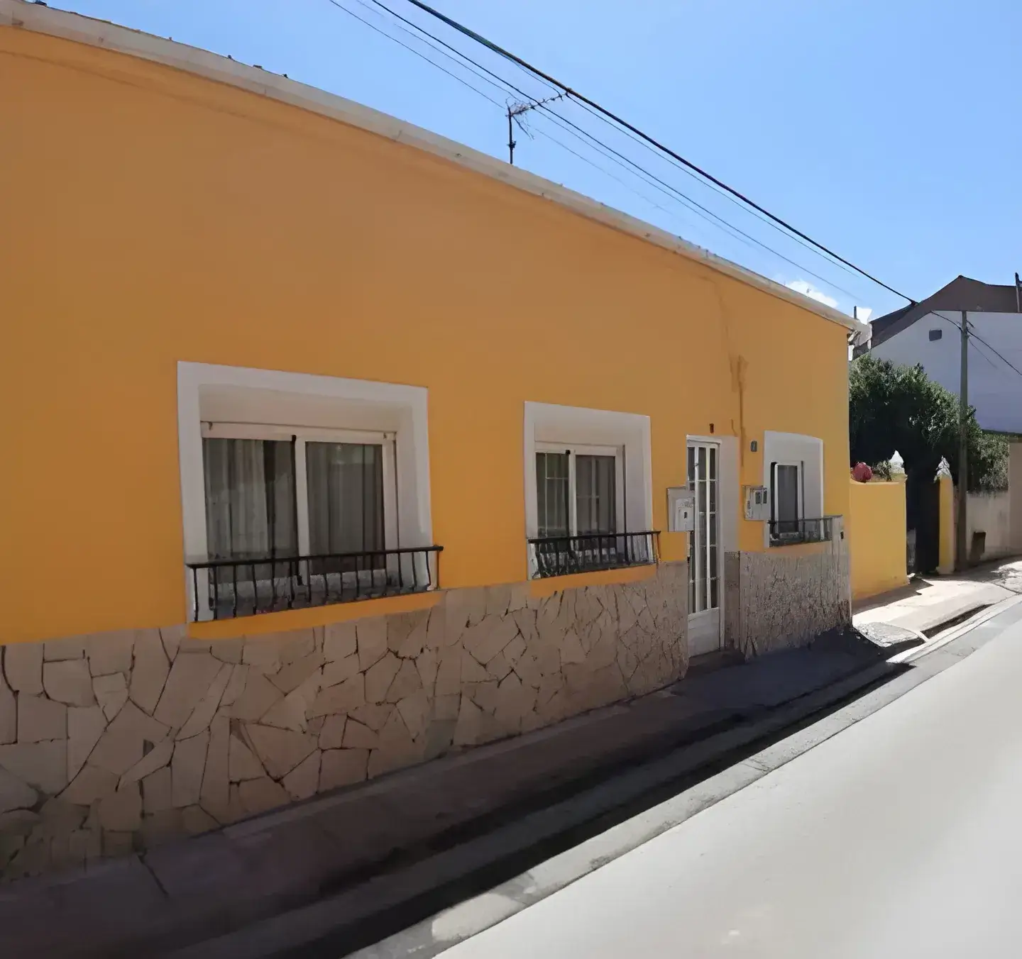 Pintores en Badajoz Fachada de casa tradicional pintada en color amarillo con zócalo de piedra